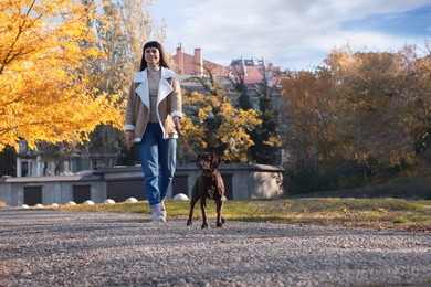 Woman with her German Shorthaired Pointer dog walking outdoors, space for text