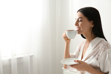 Woman with cup of coffee in bedroom. Lazy morning