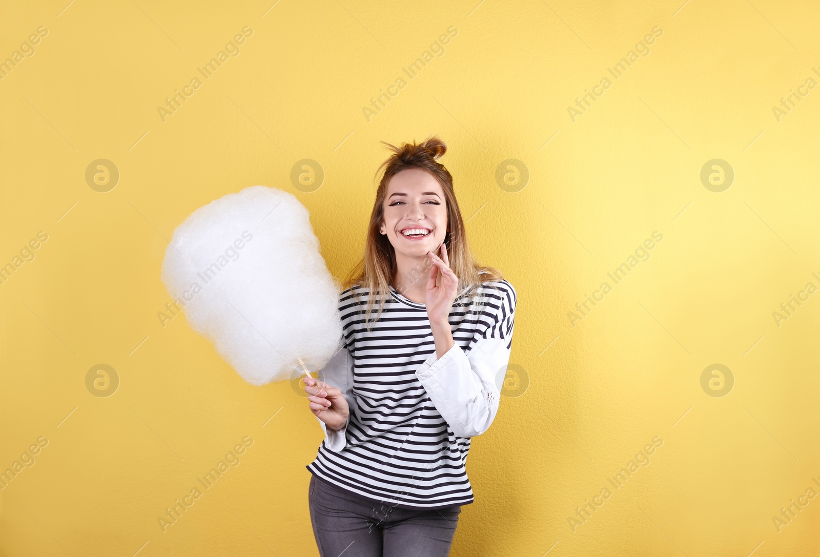 Photo of Young pretty woman with cotton candy on colorful background