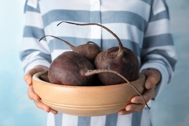 Photo of Woman holding bowl with beets on light background