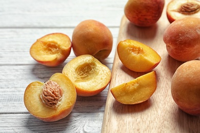 Delicious ripe peaches and cutting board on table, closeup