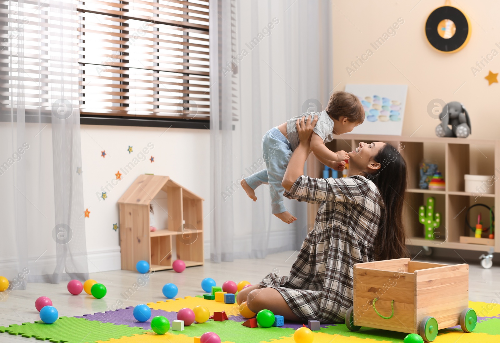 Photo of Young nanny playing with cute little baby at home