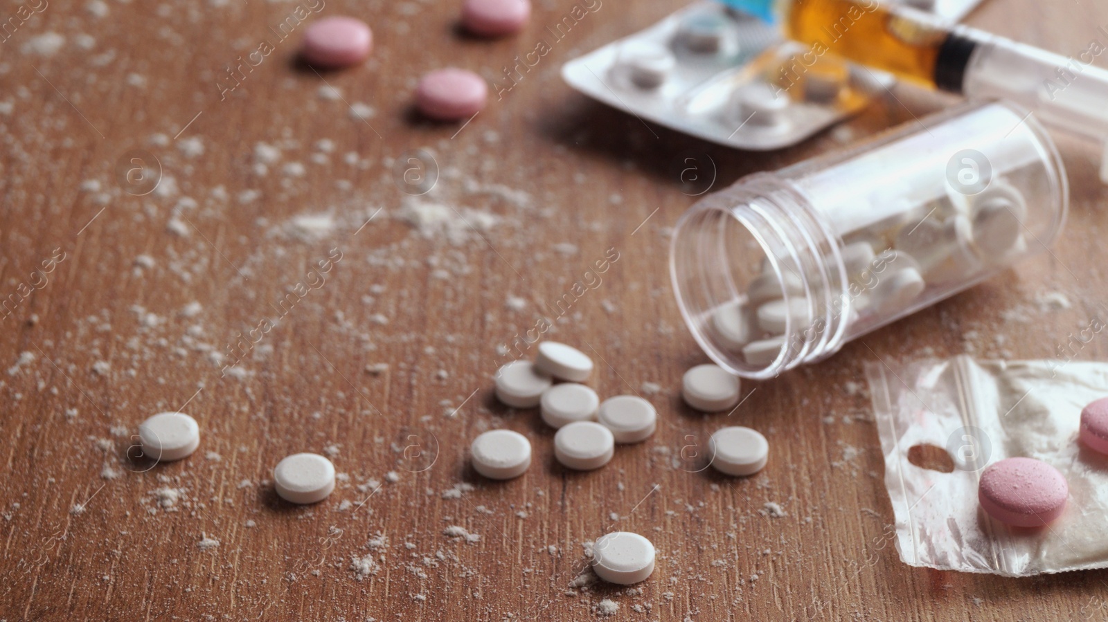 Photo of Pills, syringes and powder on wooden table, closeup. Hard drugs