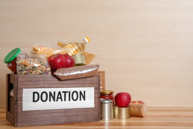 Photo of Donation box with food on table against light background. Space for text