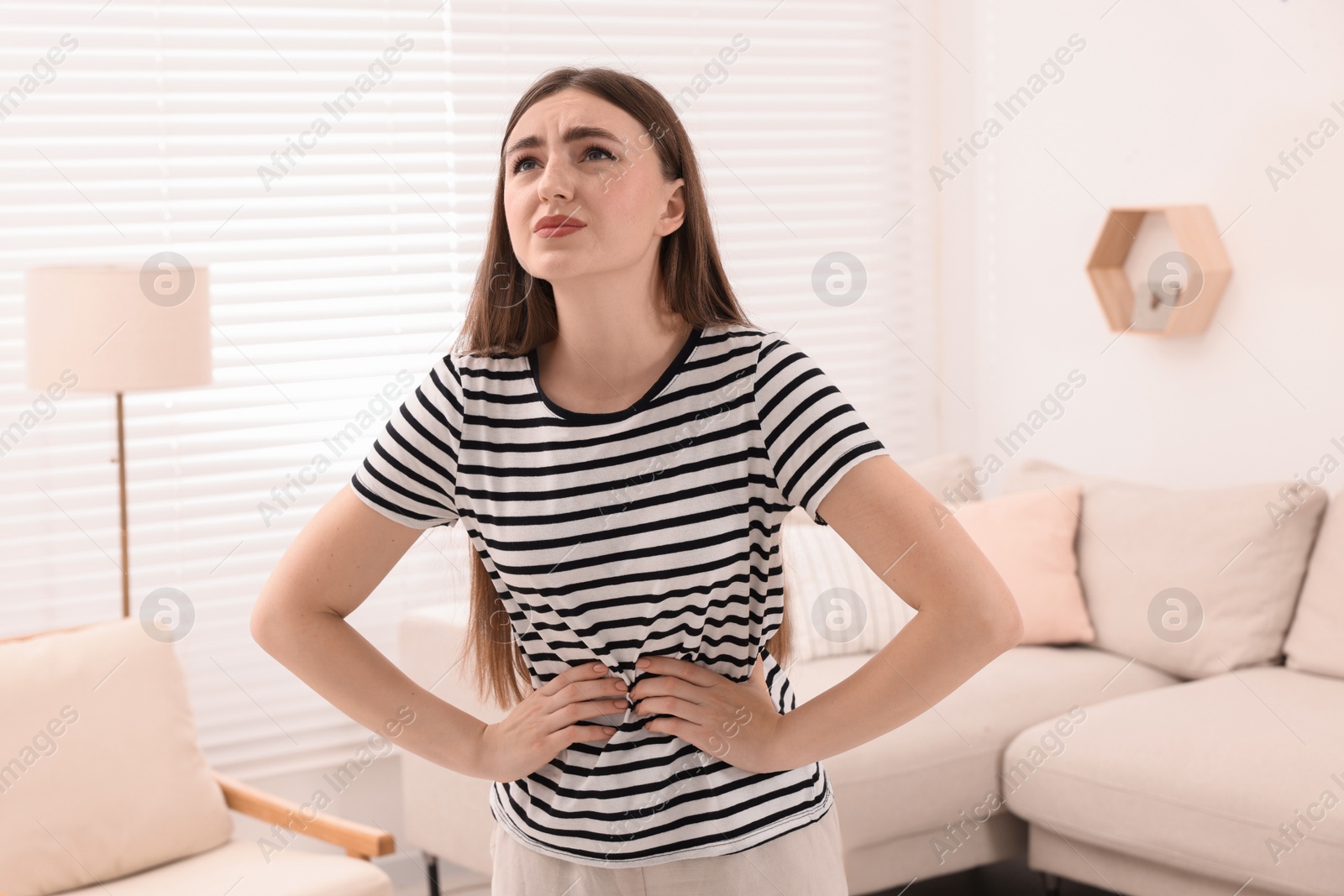 Photo of Young woman suffering from stomach pain at home