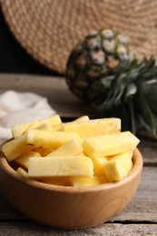 Photo of Pieces of tasty ripe pineapple in bowl on wooden table, closeup. Space for text