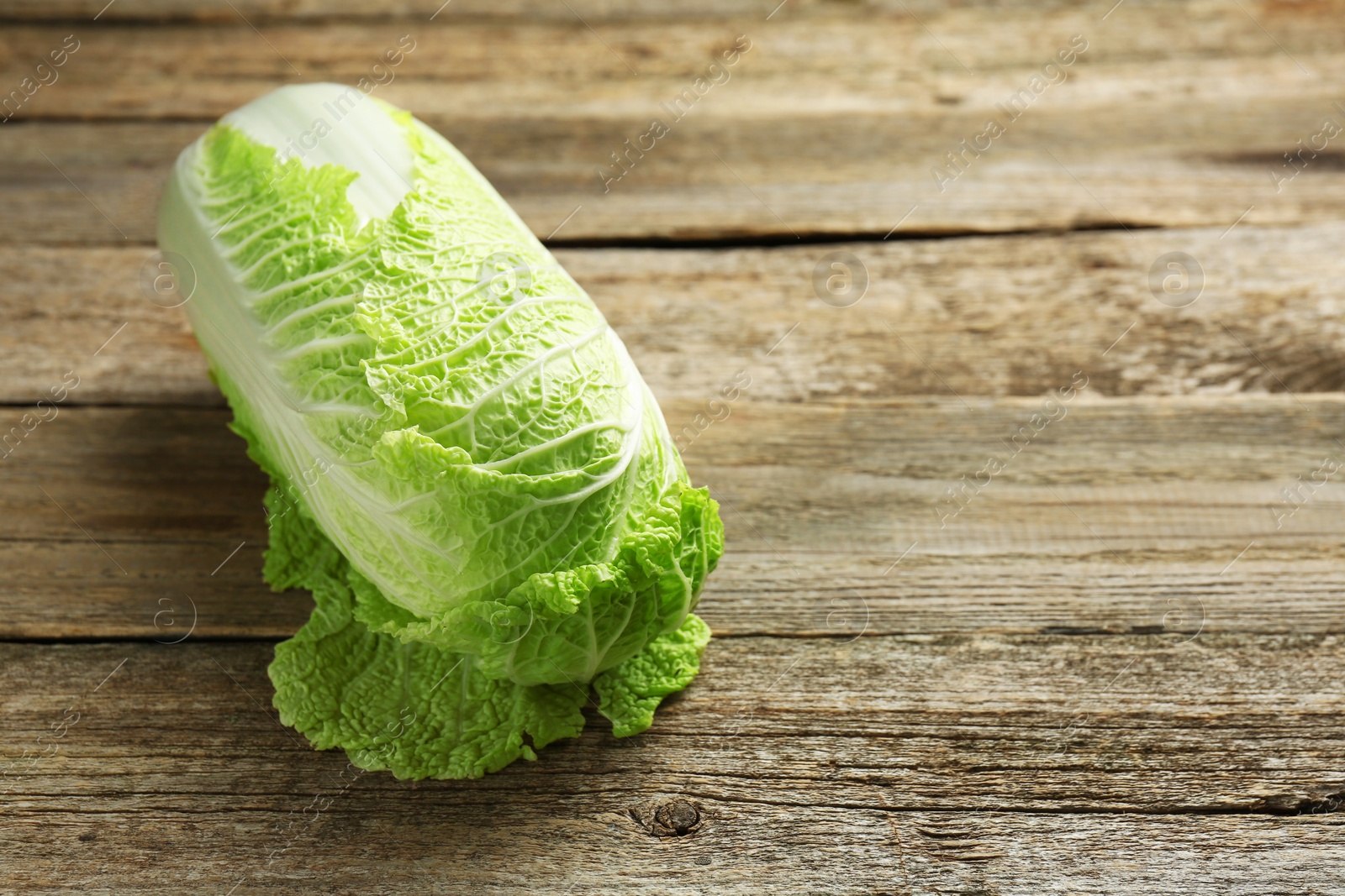 Photo of Fresh ripe Chinese cabbage on wooden table, space for text