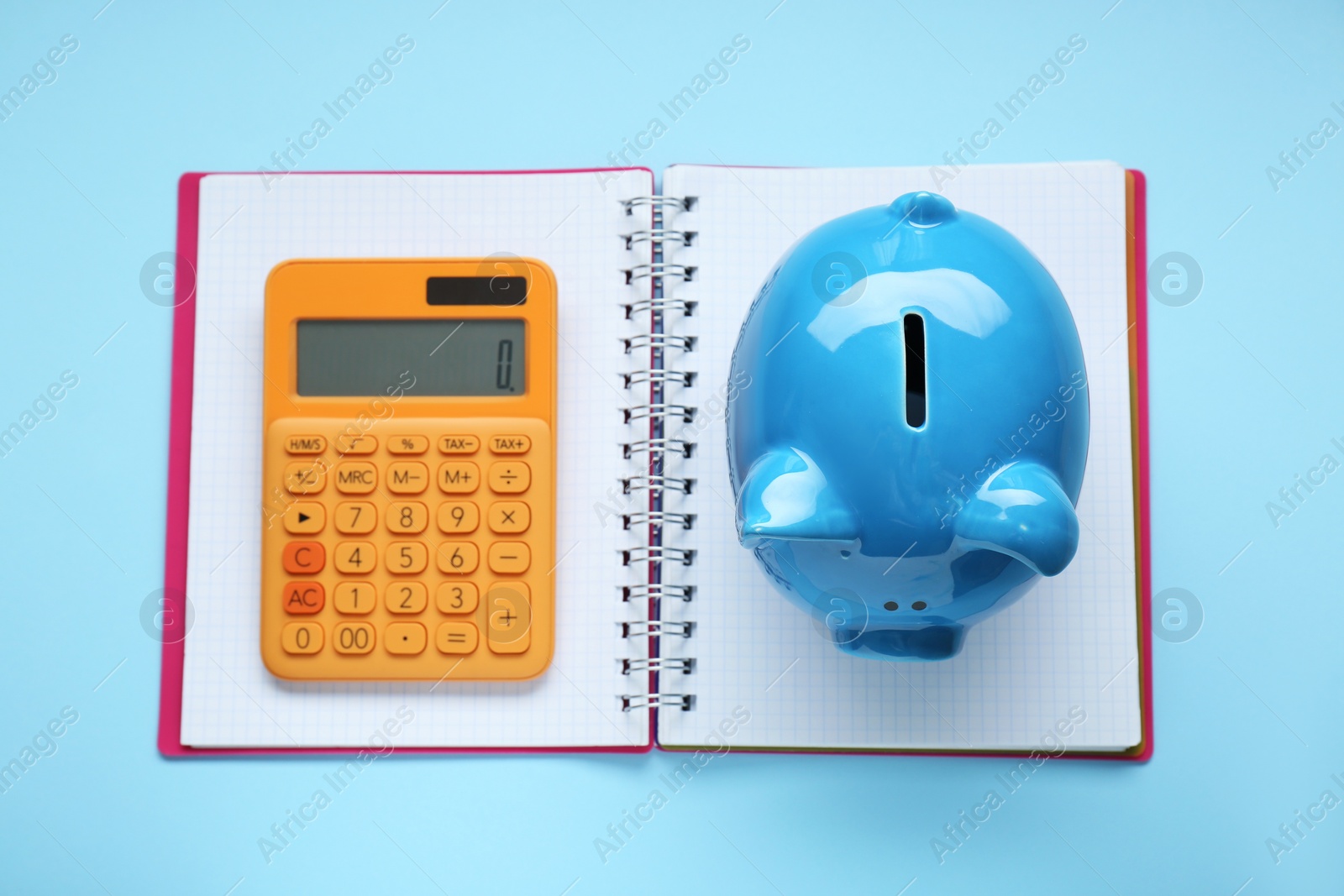 Photo of Piggy bank, notebook and calculator on light blue background, top view