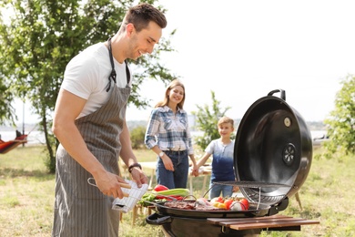 Photo of Happy family having barbecue with modern grill outdoors