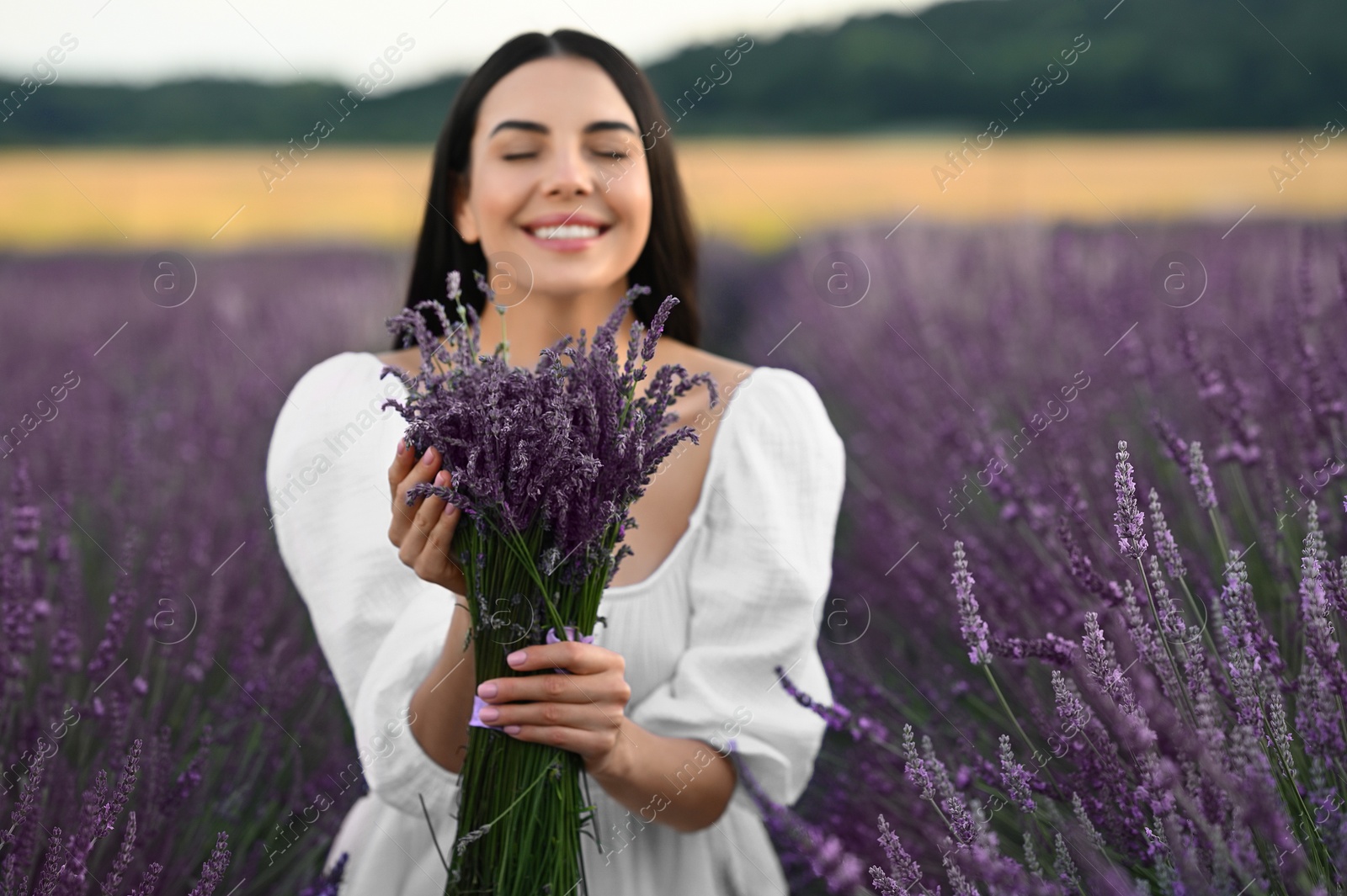 Photo of Beautiful young woman with bouquet in lavender field