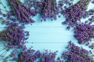 Photo of Frame with lavender flowers on light blue wooden table, flat lay. Space for text
