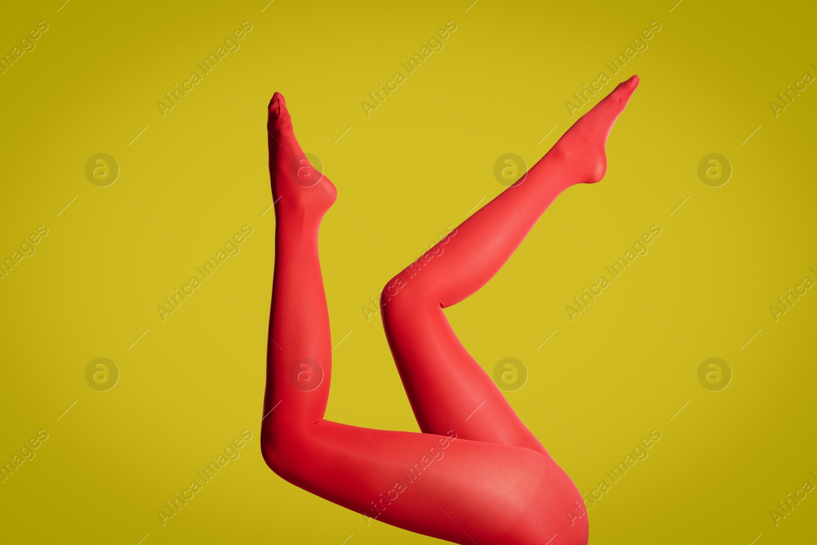 Photo of Woman wearing red tights on yellow background, closeup of legs