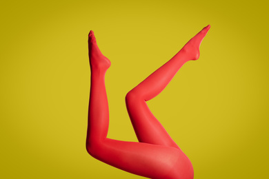 Photo of Woman wearing red tights on yellow background, closeup of legs