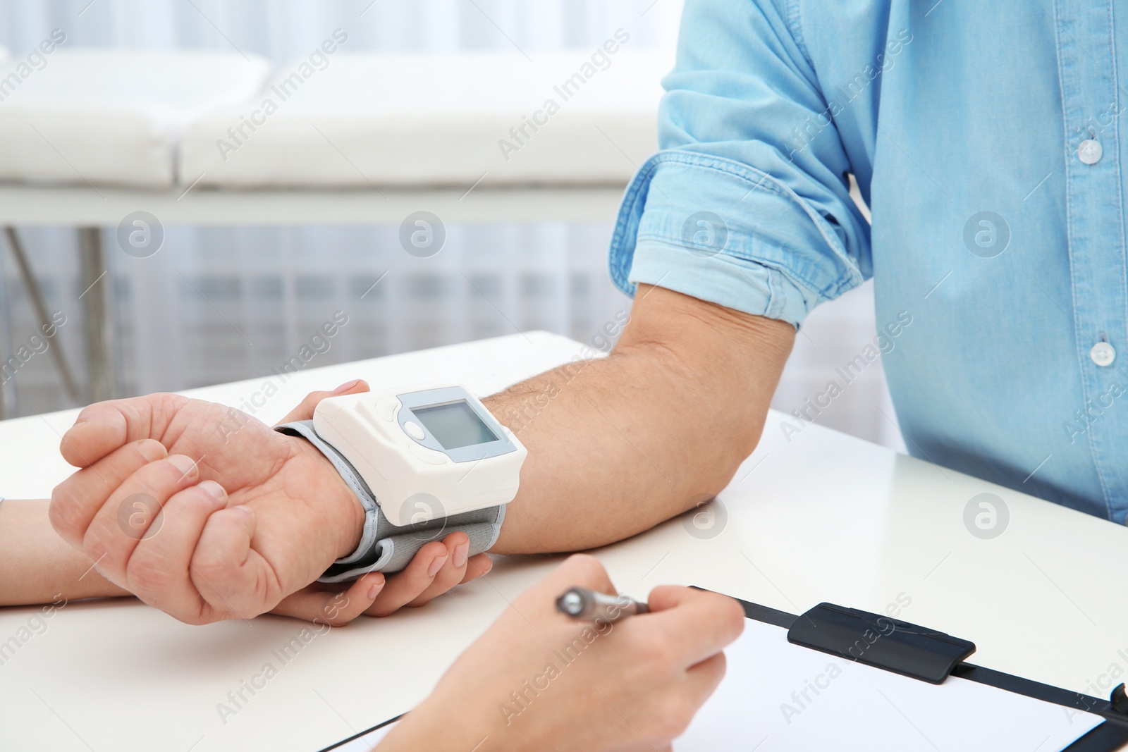 Photo of Doctor checking mature man's pulse with medical device in hospital, closeup