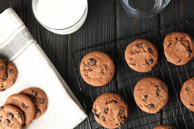 Cooling rack with chocolate chip cookies on wooden background, flat lay