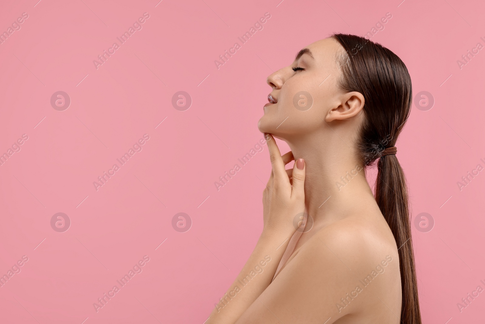 Photo of Beautiful woman touching her chin on pink background. Space for text