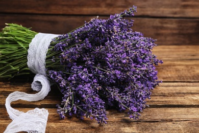 Photo of Beautiful fresh lavender bouquet with lace ribbon on wooden table