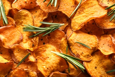 Photo of Sweet potato chips with rosemary as background, top view