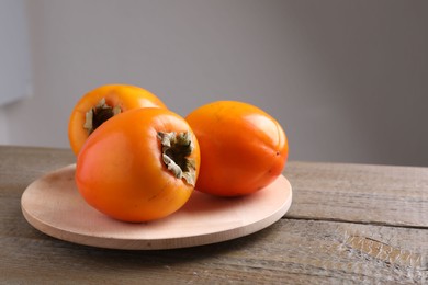 Photo of Delicious ripe persimmons on wooden table. Space for text