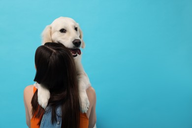 Photo of Woman with cute Labrador Retriever dog on light blue background, space for text. Adorable pet