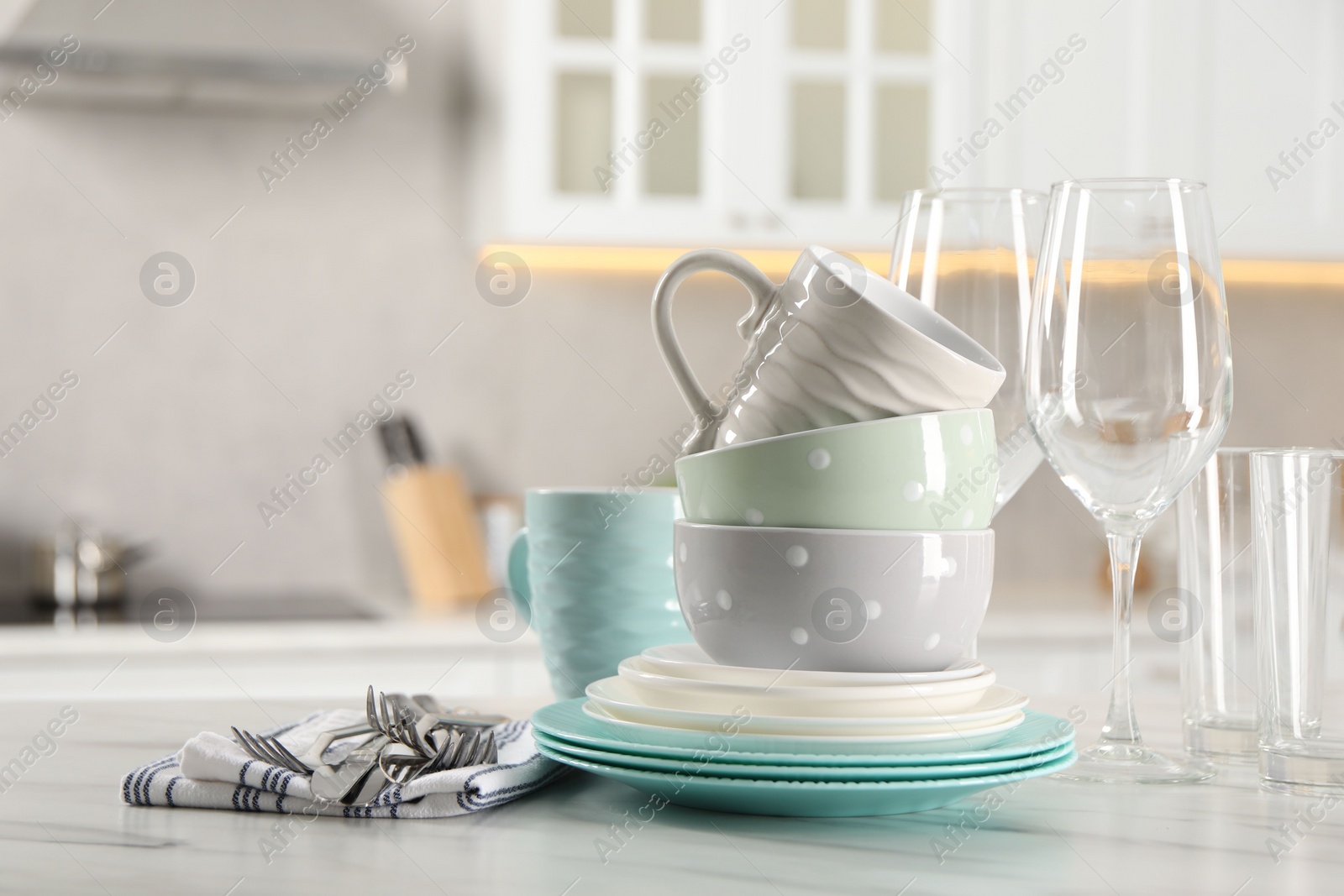 Photo of Many different clean dishware, cutlery, glasses and cups on white marble table in kitchen