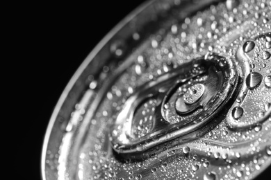 Photo of Aluminum can of beverage covered with water drops on black background, closeup