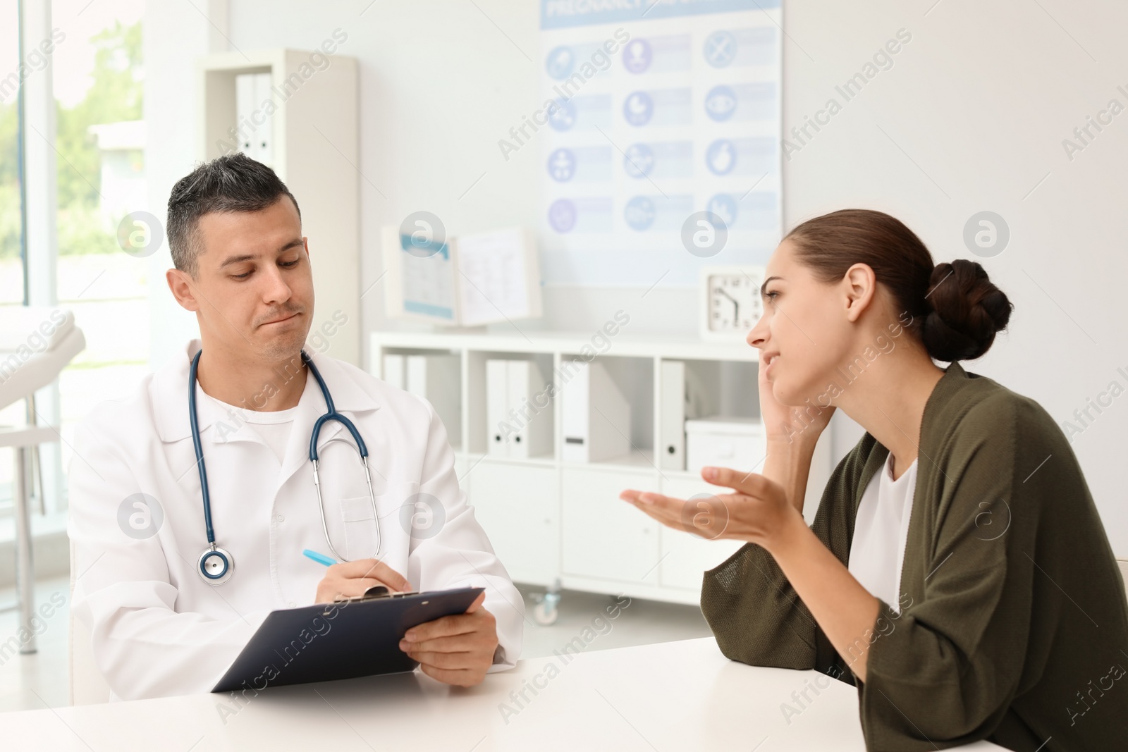 Photo of Young doctor listening to patient's complaints in hospital