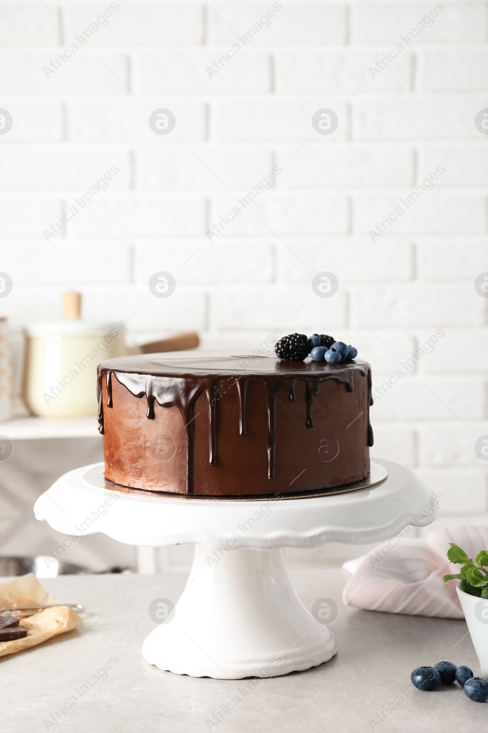 Photo of Fresh delicious homemade chocolate cake with berries on table against brick wall