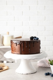 Photo of Fresh delicious homemade chocolate cake with berries on table against brick wall