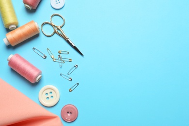 Photo of Flat lay composition with scissors and other sewing accessories on light blue background. Space for text