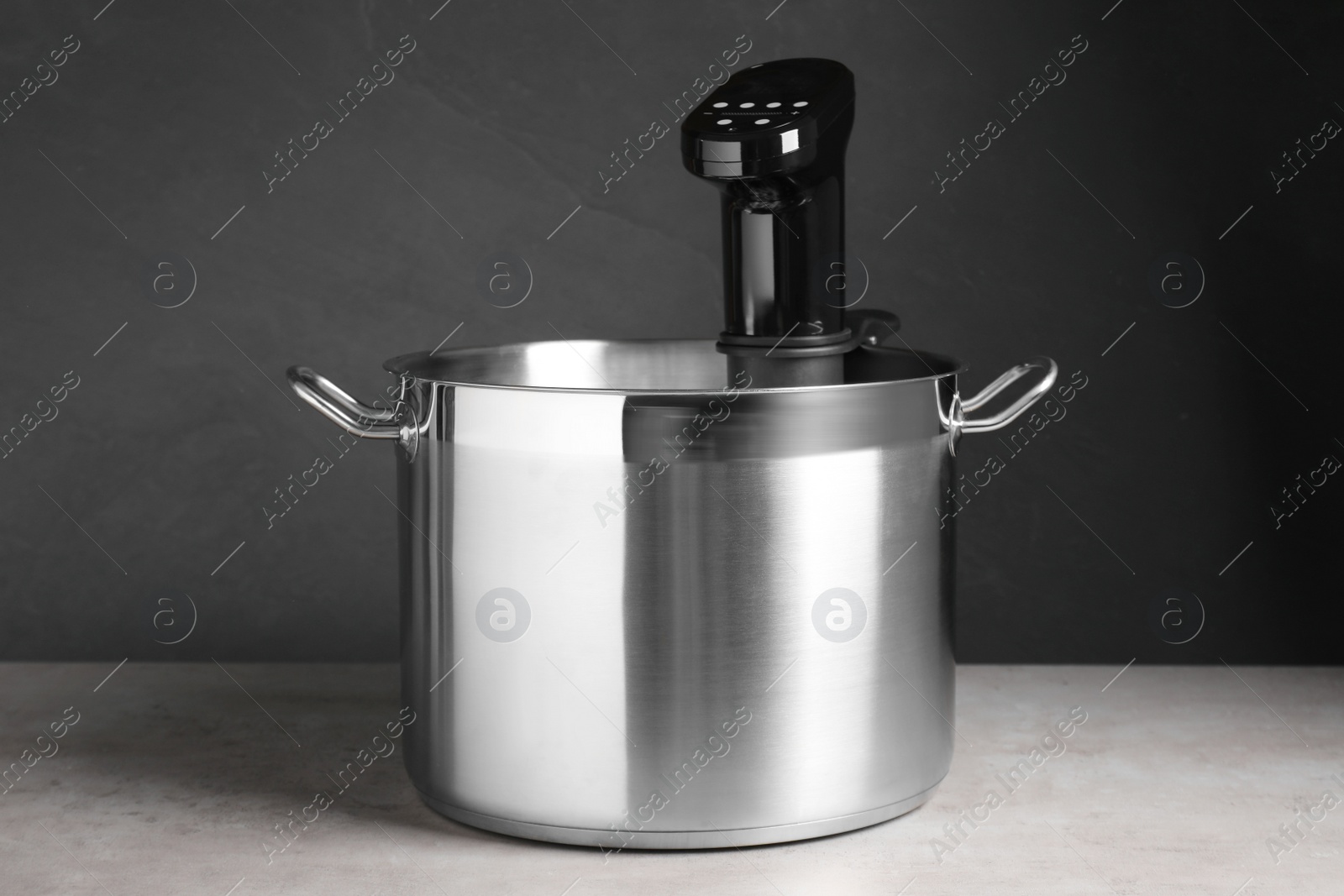 Photo of Sous vide cooker in pot on light grey table. Thermal immersion circulator