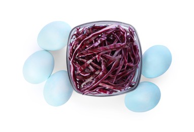 Photo of Light blue Easter eggs painted with natural dye and red shredded cabbage on white background, top view