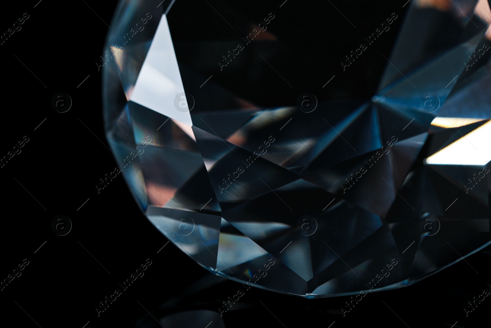 Photo of Large dazzling brilliant on black glass surface, closeup