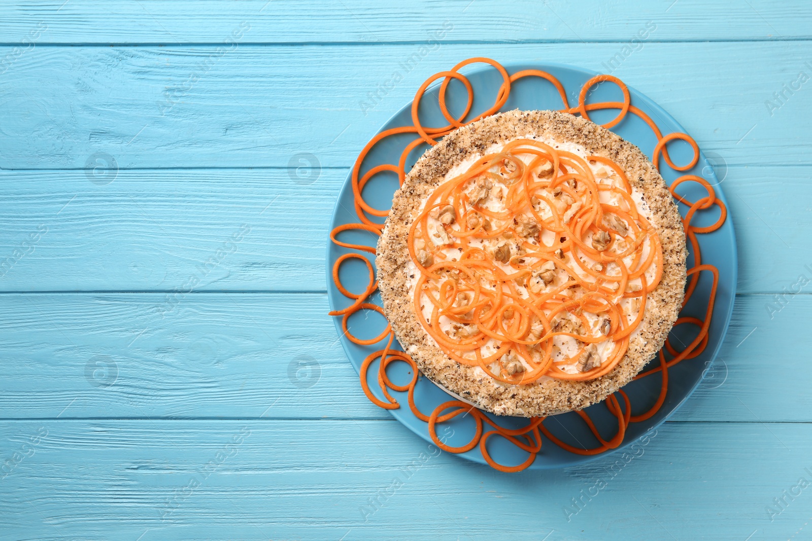 Photo of Dish with delicious carrot cake on blue wooden background, top view. Space for text