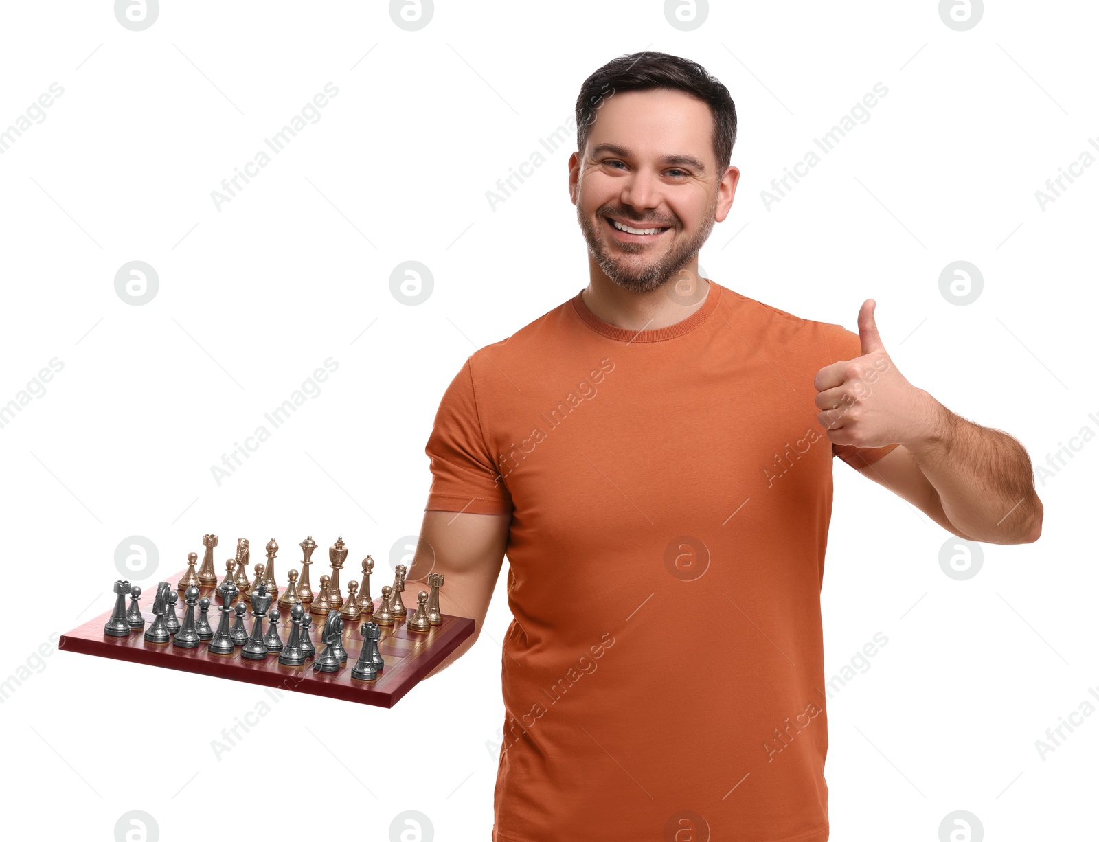 Photo of Smiling man holding chessboard with game pieces and showing thumbs up on white background