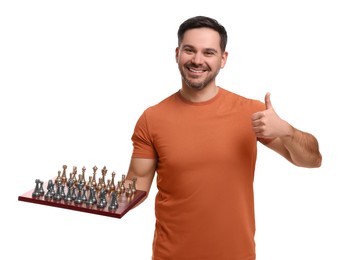 Smiling man holding chessboard with game pieces and showing thumbs up on white background