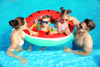 Photo of Young family with little children in swimming pool on sunny day