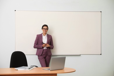 Photo of Female teacher near whiteboard in modern classroom