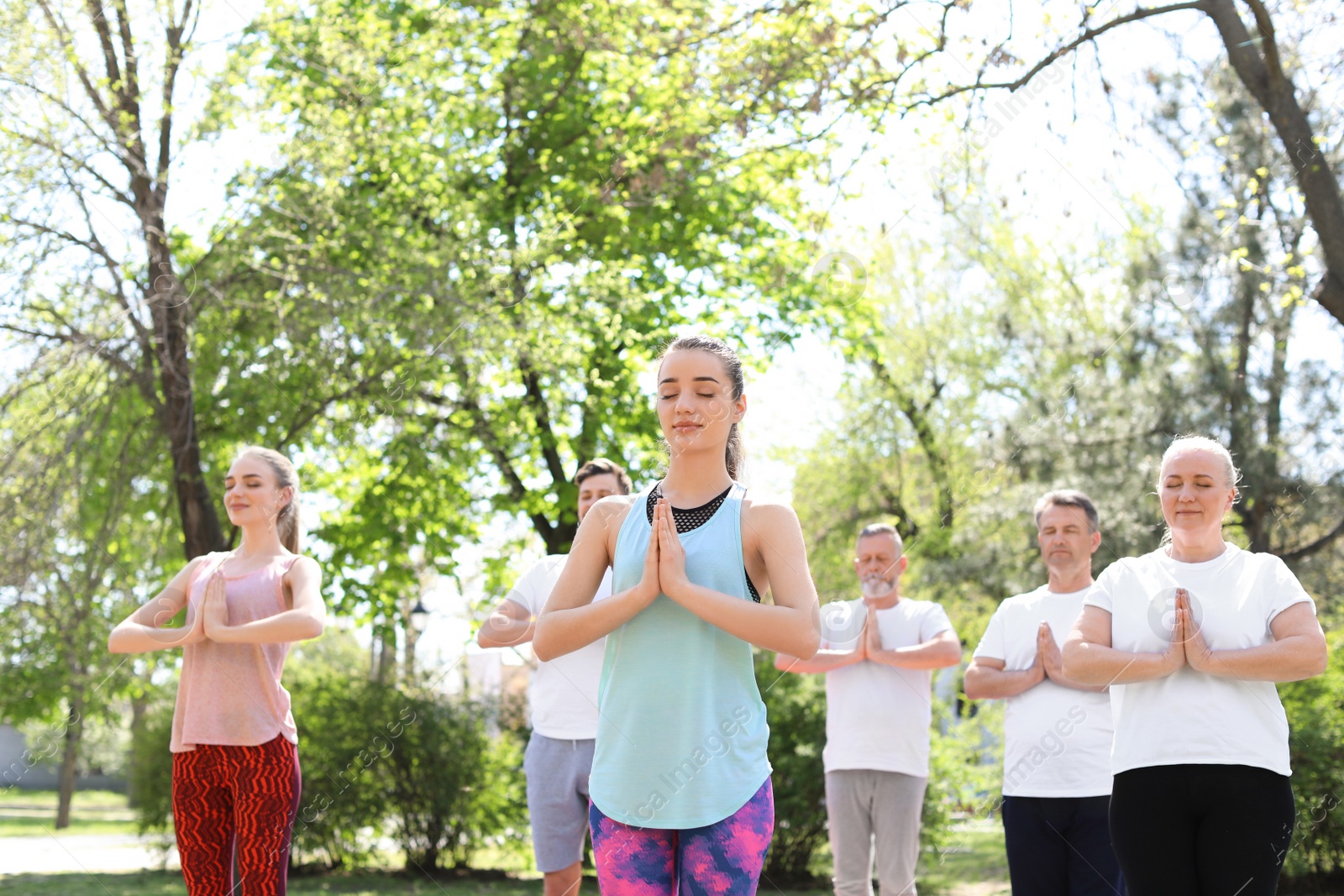 Photo of Group of people practicing yoga in park on sunny day