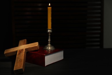 Church candle, Bible and wooden cross on table, space for text