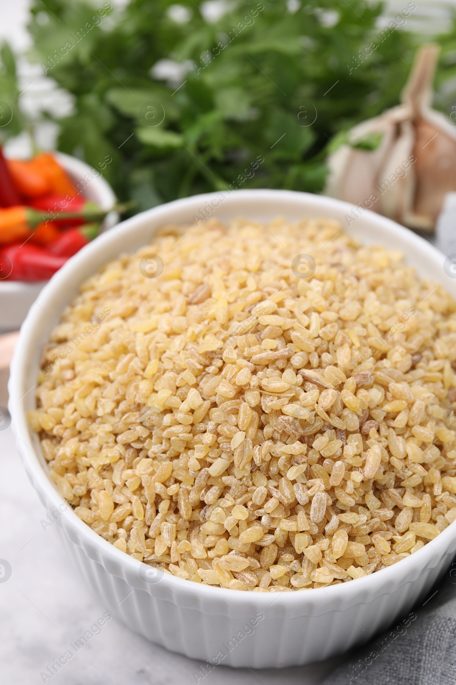 Photo of Raw bulgur in bowl on table, closeup