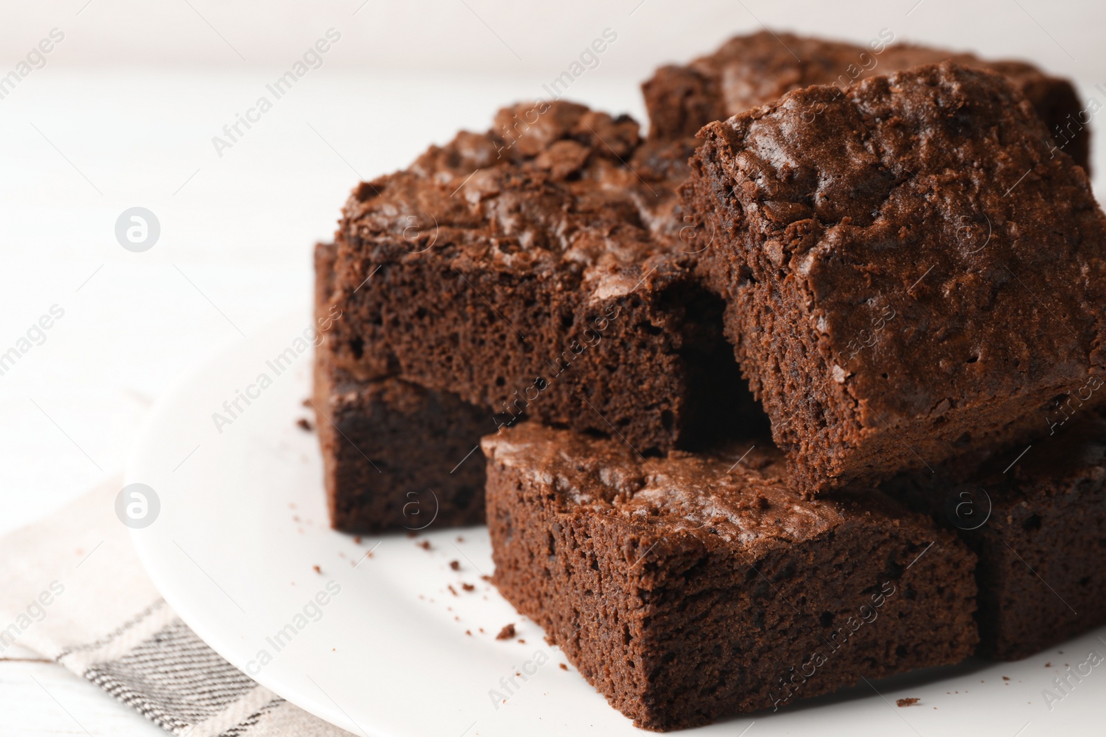 Photo of Plate with fresh brownies on white table, space for text. Delicious chocolate pie