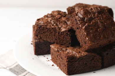 Plate with fresh brownies on white table, space for text. Delicious chocolate pie