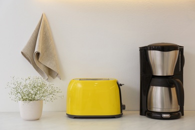 Modern toaster, coffee machine and flowers on counter in kitchen