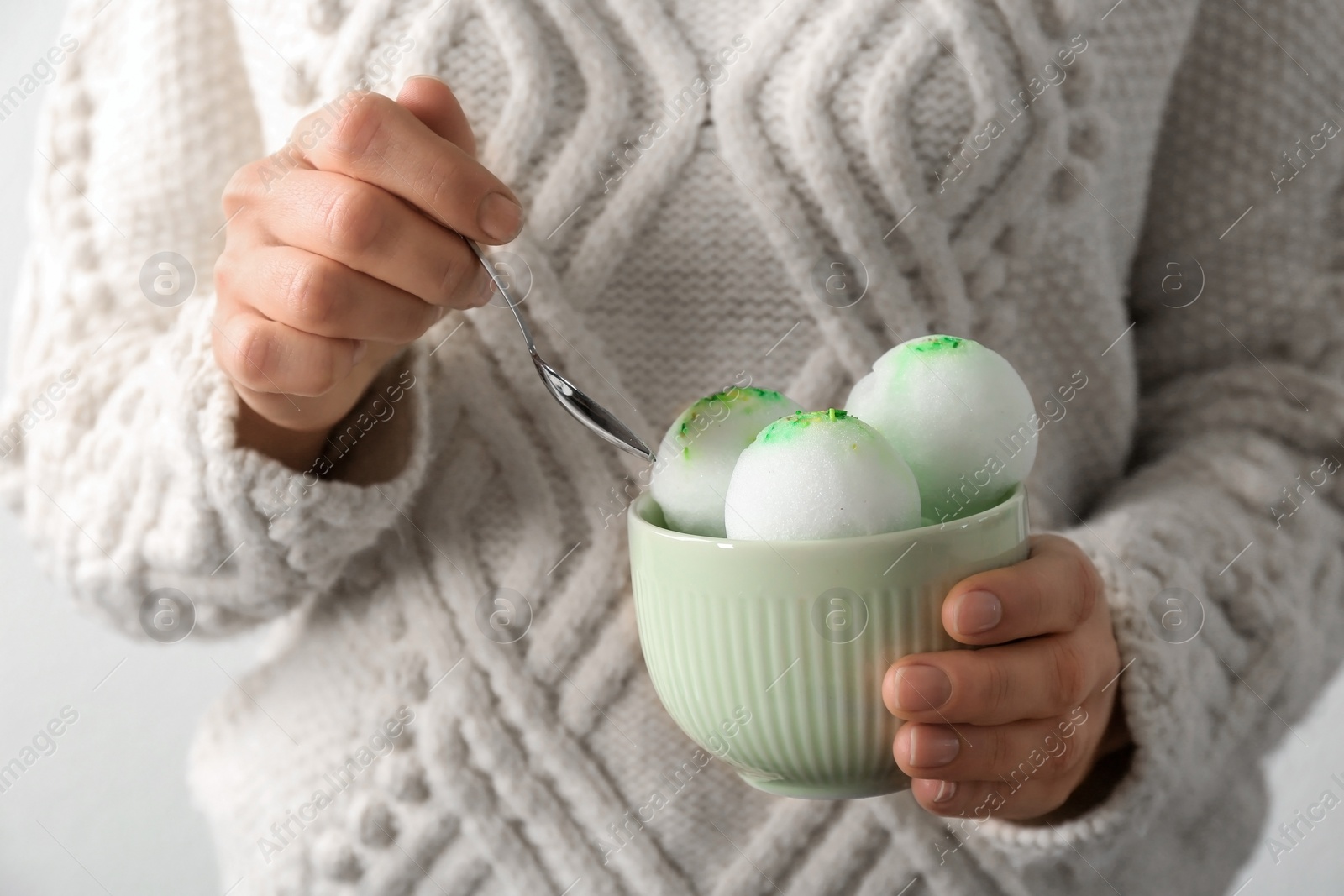 Photo of Woman eating snow ice cream from bowl on light background, closeup