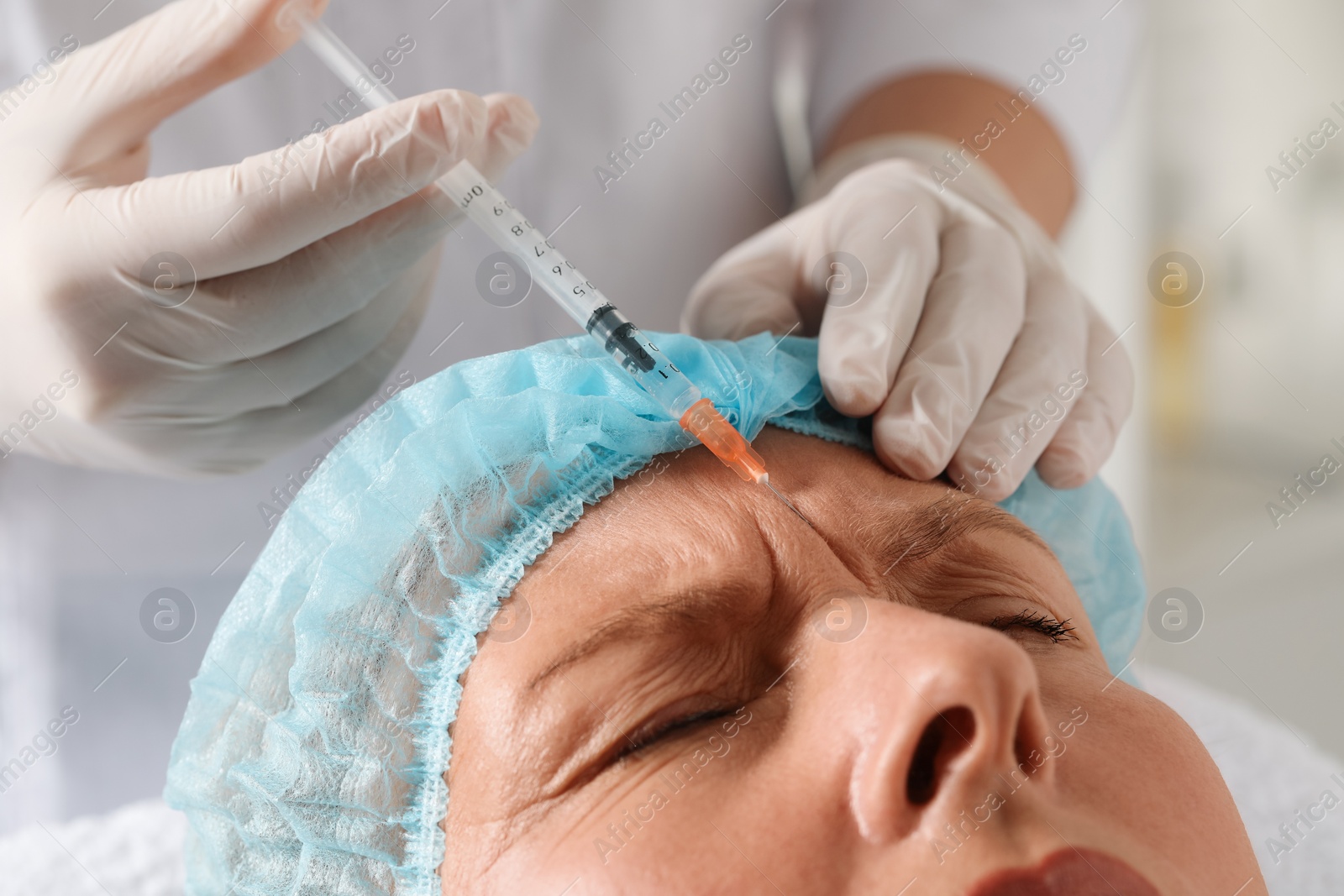 Photo of Doctor giving facial injection to senior woman in clinic, closeup. Cosmetic surgery