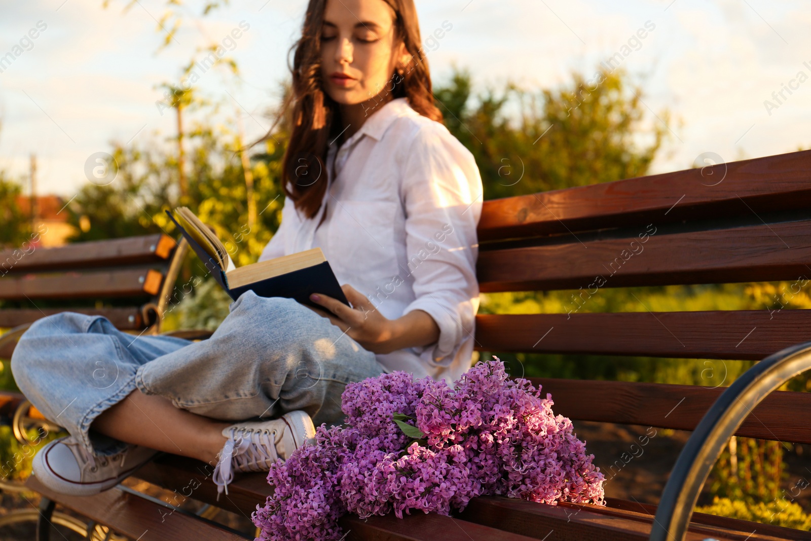 Photo of Beautiful young woman reading on bench in park