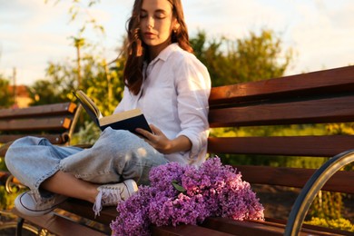 Photo of Beautiful young woman reading on bench in park