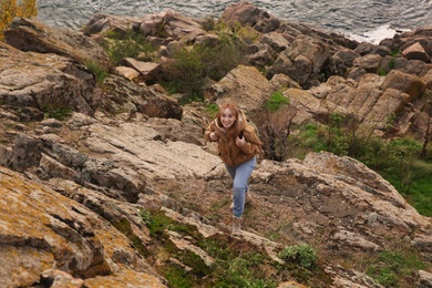 Photo of Woman with backpack climbing up mountains on autumn day