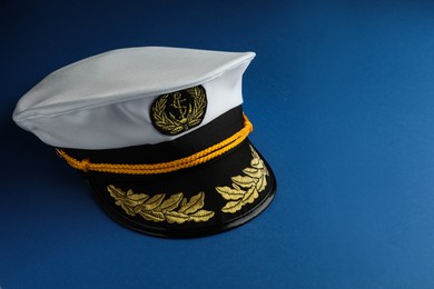Photo of Peaked cap with accessories on blue background, space for text